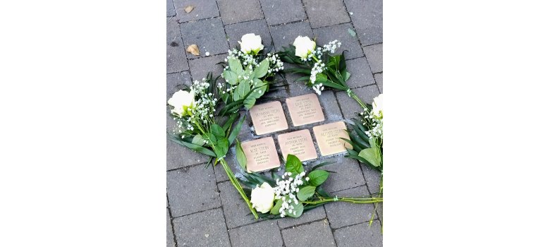 Stolpersteine umrahmt von weißen Rosen